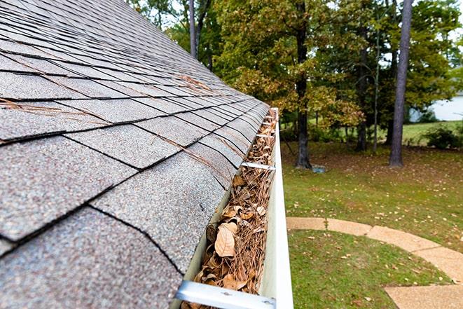 a homeowner clearing out clogged gutters